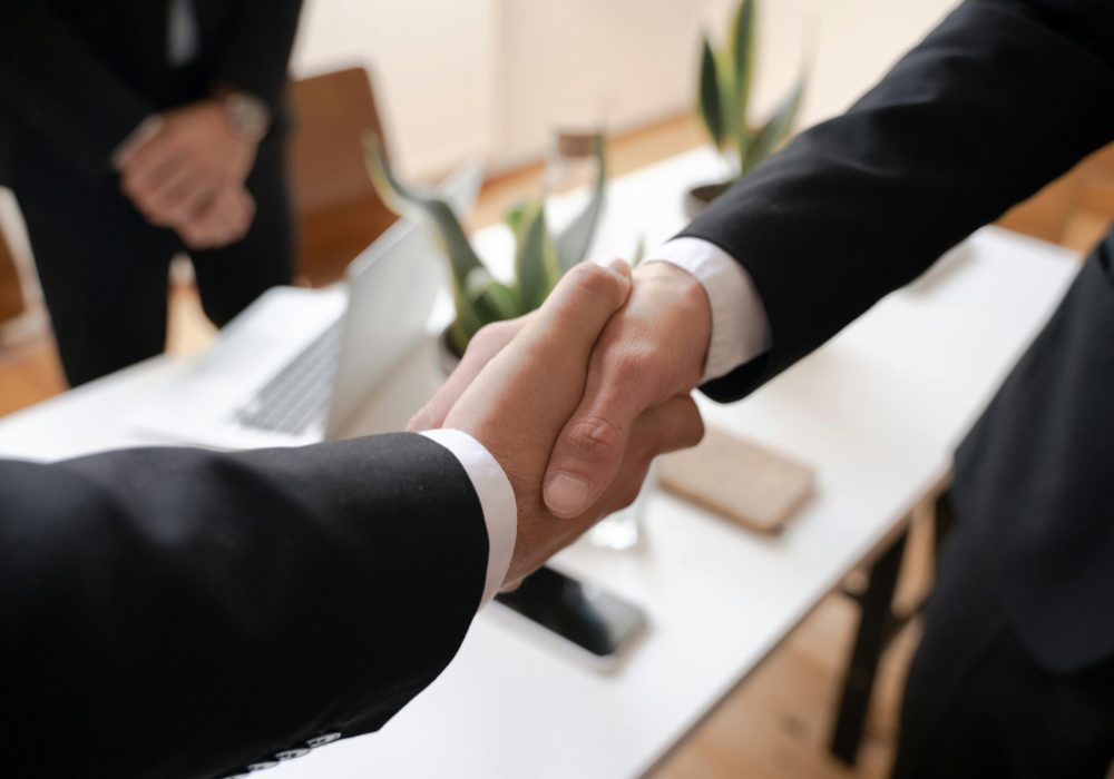 Close-up of a handshake between two professionals in a business setting, symbolizing agreement.